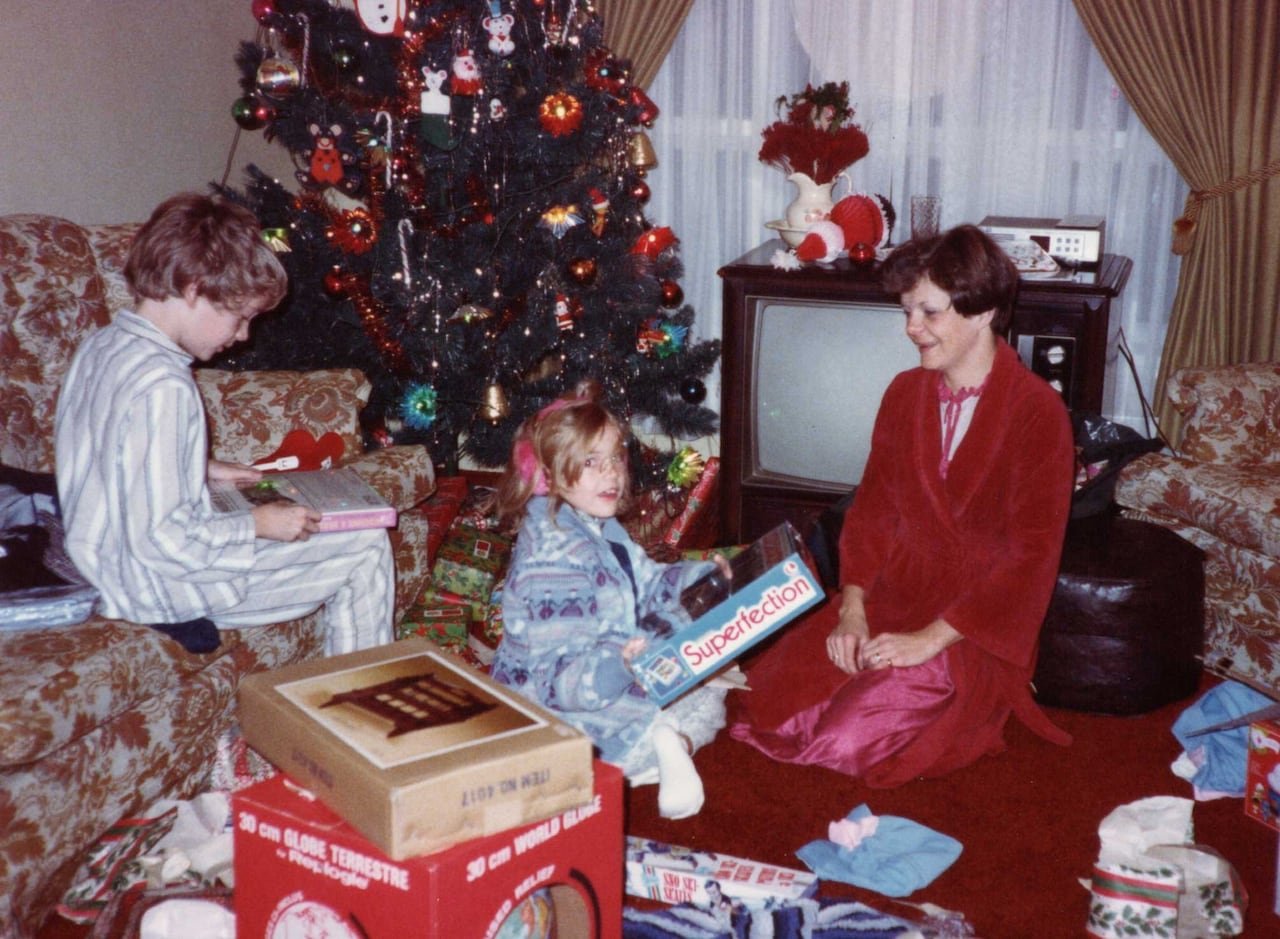 default-200 An old photograph showing a boy, a girl and their mother opening gifts on Christmas morning.